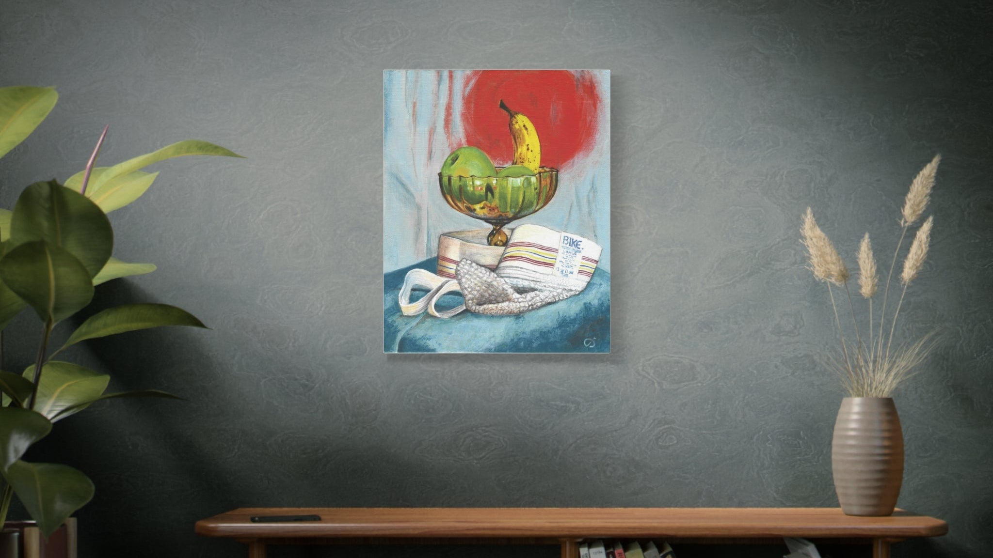 Gay wall art painting of a glass bowl with fruit and a red circle and a white Bike jockstrap on a wall above a wooden shelf with books and decor.
